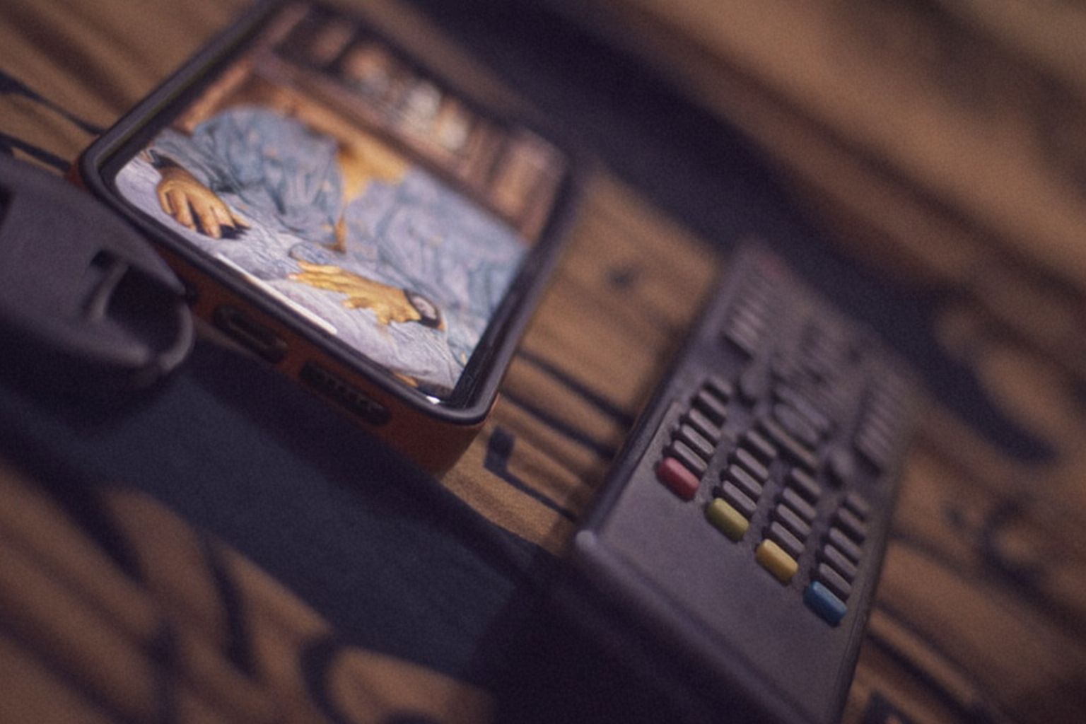 Mobiltelefon visar spel på skärmen bredvid fjärrkontroll.