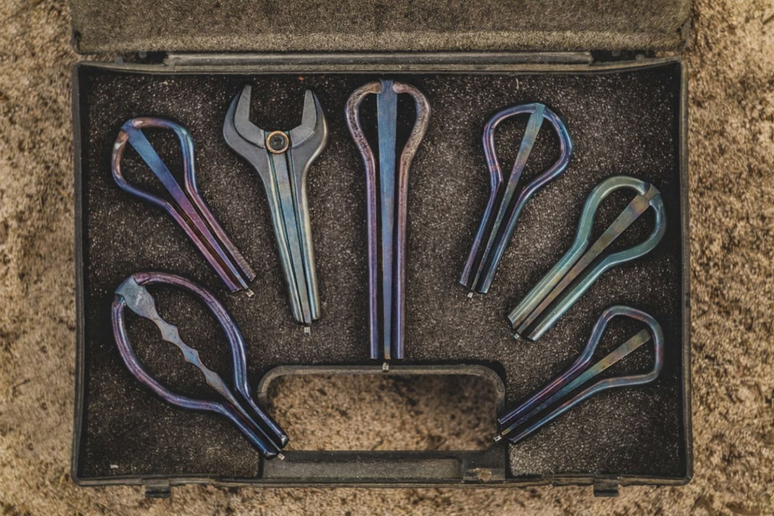 Olika metallinstrument som liknar mungigor i en svart verktygslåda.