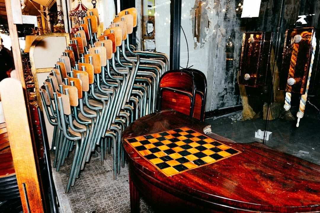 Schackbräde på ett träbord bredvid staplade caféstolar