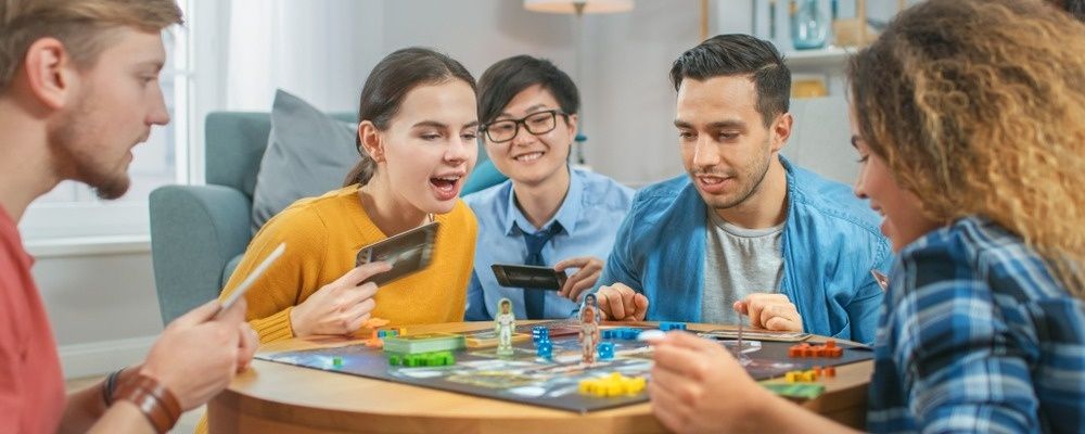 Vänner samlas runt ett brädspel och spelar tillsammans